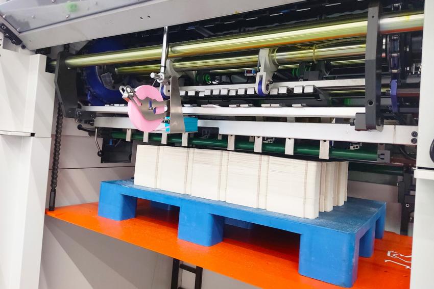 Выдвинутый в рабочее положение зеленый фартук НОН-СТОП приемки + ровно уложенная стопа, очищенная от облоя по 4-м сторонам + устройство вставки закладок – стандартные функция для STERLING S-CUT 106C