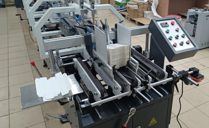 Самонаклад FoldLINE-600 уснащен индивидуально регулируемыми рифлеными ремнями, вибросталкивателем, удобным столиком для размещения заготовок и передними упорами с роликовой протяжкой и устройством быстрого подъема ручкой